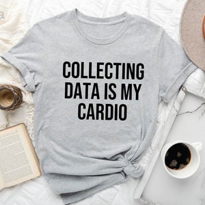Pu&ograve; includere: Una maglietta grigia chiaro con la scritta "COLLECTING DATA IS MY CARDIO" stampata in nero.