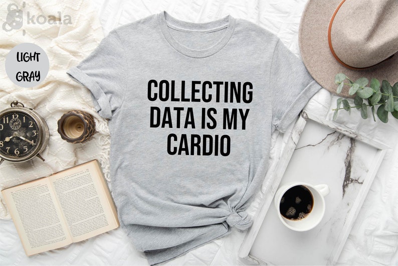Pu&ograve; includere: Una maglietta grigia chiaro con la scritta "COLLECTING DATA IS MY CARDIO" stampata in nero.