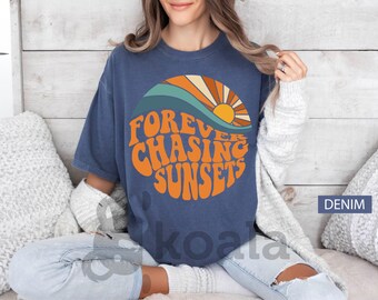 May include: A navy blue t-shirt with a retro-style graphic of a sunset and the text "FOREVER CHASING SUNSETS".
