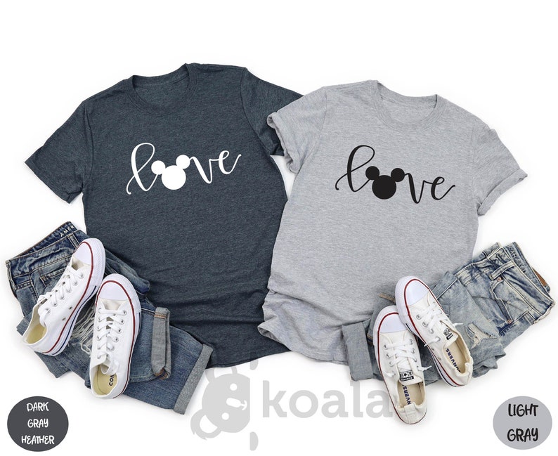 May include: Two t-shirts with the word "love" written in cursive with a Mickey Mouse head replacing the "o". One shirt is dark heather gray and the other is light gray.