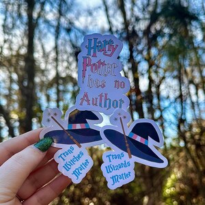 May include: Three stickers with a Harry Potter theme. The top sticker says "Harry Potter has no Author". The bottom two stickers say "Trans Witches Matter" and "Trans Wizards Matter".