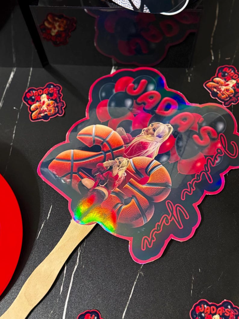 May include: A holographic basketball-themed cake topper with the text "Jada's 25th Year" in red script. The topper features a basketball player and basketballs. Additional stickers with text are also visible.