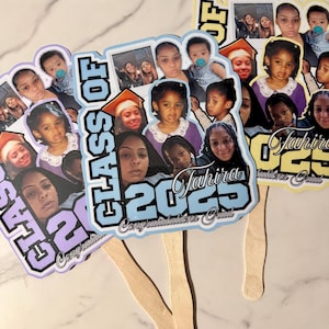 May include: Three graduation fan favors with photos of people. The fans have a light blue, purple, and yellow color scheme. The text "Class of 2023" and "Congratulations Grad" are visible on the fans.