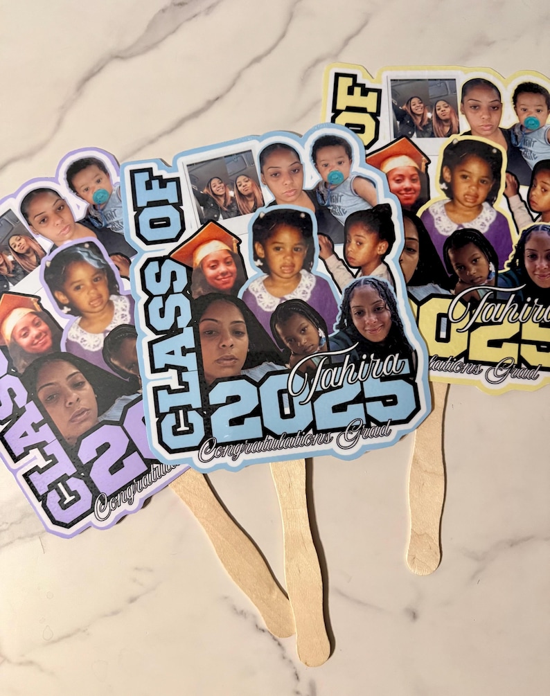 May include: Three graduation fan favors with photos of people. The fans have a light blue, purple, and yellow color scheme. The text "Class of 2023" and "Congratulations Grad" are visible on the fans.