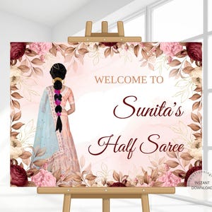 May include: A welcome sign for "Sunita's Half Saree" event. The sign features a watercolor illustration of a woman in traditional Indian attire, surrounded by floral elements in shades of pink, burgundy, and beige. The text "WELCOME TO" and "Sunita's Half Saree" are displayed.