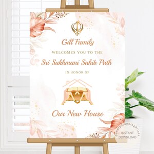 Pode incluir: Uma placa de boas-vindas retangular num cavalete com um símbolo Khanda dourado, detalhes florais em aguarela cor de pêssego e creme, e o texto: Gill Family welcomes you to the Sri Sukhmani Sahib Path in honor of our new house.
