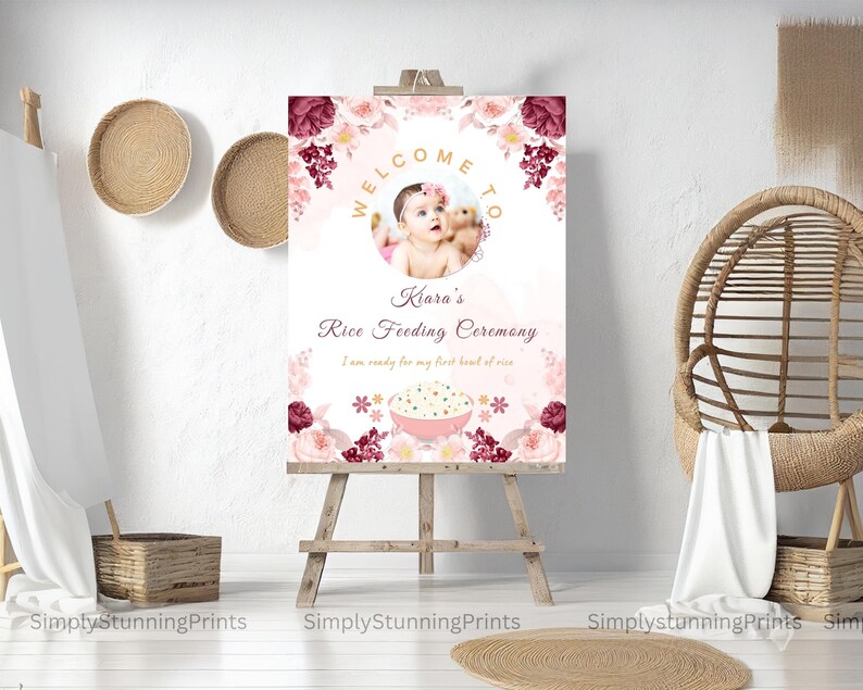 Pode incluir: Um cartaz de boas-vindas rosa e branco com detalhes florais e uma foto de uma menina pequena. O cartaz diz "Bem-vindo &agrave; Cerim&ocirc;nia de Alimenta&ccedil;&atilde;o de Arroz da Kiara. Estou pronta para minha primeira tigela de arroz."