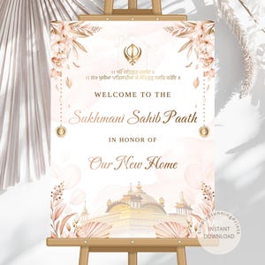 May include: A welcome sign on a wooden easel. The sign is white with gold and peach accents, floral designs, and text that reads "Welcome to the Sukhmani Sahib Paath in Honor of Our New Home."