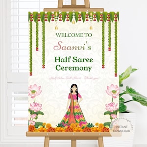 Könnte beinhalten: Ein Schild auf einer Staffelei mit der Aufschrift "Willkommen zu Saanvis Half Saree Ceremony". Das Design umfasst eine Frau in traditioneller Kleidung, Lotusblumen und Girlanden. Das Schild ist mit grünen und roten Girlanden verziert.