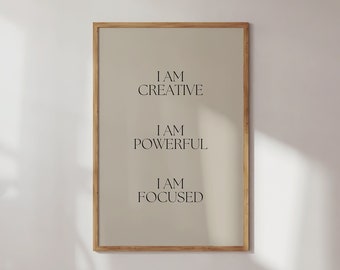 May include: A framed beige poster with the text "I AM CREATIVE", "I AM POWERFUL", and "I AM FOCUSED" in black text.