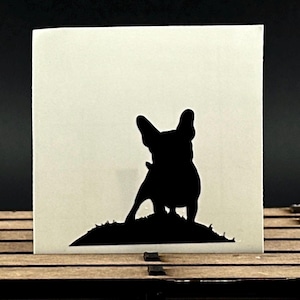 Matte black vinyl decal featuring a detailed French bulldog standing in a small hill, displayed against a white background.
