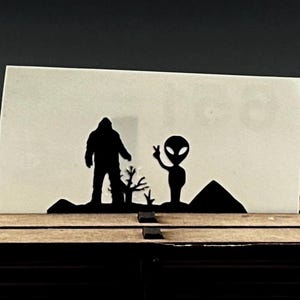 Calcomanía de vinilo de Pie Grande y extraterrestre: divertida calcomanía de huevo de Pascua de críptido para auto, camioneta, laptop y botella de agua. Calcomanía para ventana de Pie Grande.