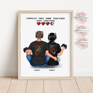 Peut inclure: Impression encadrée avec deux personnages dos à dos, vêtus de t-shirts noirs avec des motifs de manettes de jeu. Le texte "COUPLES THAT GAME TOGETHER STAY TOGETHER" est en haut, avec les noms "CASEY" et "DARCY" en dessous.