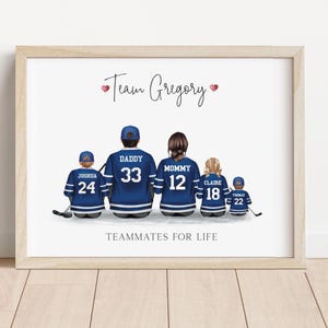 K&ouml;nnte beinhalten: Gerahmter Druck mit einer Familie von f&uuml;nf Personen in Hockey-Trikots. Die blauen Trikots haben wei&szlig;e Streifen und sind mit Namen und Nummern personalisiert. Der Text "Team Gregory" und "Teammates for Life" ist ebenfalls enthalten.