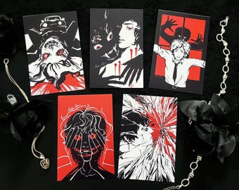 May include: Five art prints with black, white, and red illustrations. The prints depict surreal and horror-themed imagery, including figures with distorted features and ominous scenes. A silver chain and black rose are also visible.