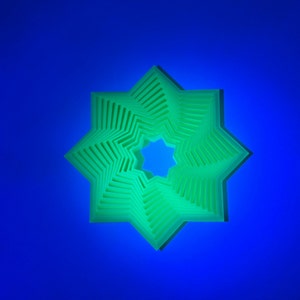 May include: A green, eight-pointed star shape with a layered design. The star is against a blue background.