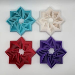 May include: Four star-shaped cookie cutters, each with a different color: turquoise, white, red, and purple. The cutters are layered to create a spiral effect.