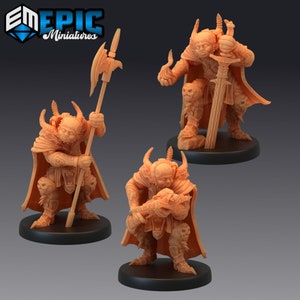 May include: Three miniature figures of a demon with horns, wearing armor and holding weapons. The figures are painted in a light brown color and are standing on black bases.
