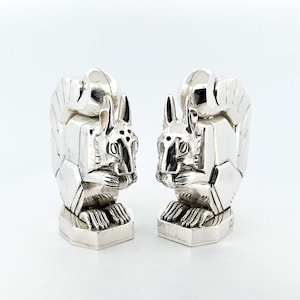 May include: A pair of silver squirrel salt and pepper shakers. The squirrels are sitting upright with their tails curled around their backs. The shakers have a hexagonal base.