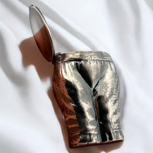 May include: A silver trinket box shaped like a pair of pants with a hinged lid.