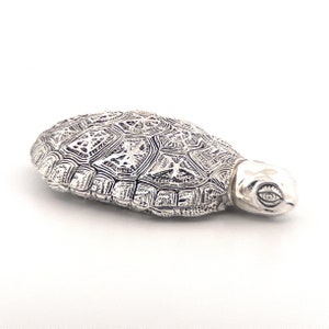 May include: A silver trinket box shaped like a turtle, with a detailed, textured shell design.