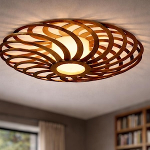 Könnte beinhalten: Eine ovale Deckenleuchte mit einem Holz-Spiraldesign. Das Licht strahlt einen warmen Schein aus und ist von gebogenen Holzlatten umgeben. Die Leuchte ist an einer weißen Decke montiert. Das Design erinnert an eine natürliche, organische Form.