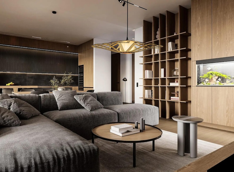Op de afbeelding: Een moderne woonkamer met een grote hoekbank in een donkergrijze stof. De bank staat voor een groot raam met natuurlijk licht. Een houten salontafel met een geometrisch ontwerp staat voor de bank. Een grote, geometrische lamp hangt aan het plafond. De kamer heeft een minimalistisch ontwerp met een focus op natuurlijke materialen.