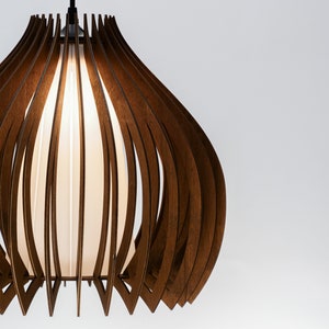 Puede incluir: Una lámpara colgante de madera marrón con una pantalla de tela blanca. La luz está hecha de finas tiras de madera que están curvadas y dispuestas en un patrón circular.