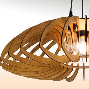 Peut inclure: Un luminaire suspendu en bois avec un design géométrique en couches. La lumière a une finition en bois naturel et comporte des ampoules apparentes. Le luminaire est suspendu au plafond par des cordons noirs, créant une esthétique moderne.