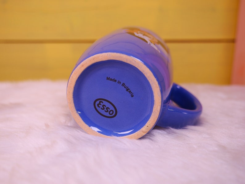 May include: Blue ceramic mug with a white logo that says "Esso" and the text "Made in Bulgaria".