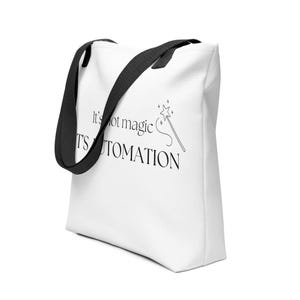 Könnte beinhalten: Weiße Tragetasche mit schwarzen Henkeln. Die Tasche trägt den Text "It's not magic, it's automation" mit einer Zeichnung eines Zauberstabs. Die Tasche ist aus robustem Material gefertigt und eignet sich zum Tragen verschiedener Gegenstände.