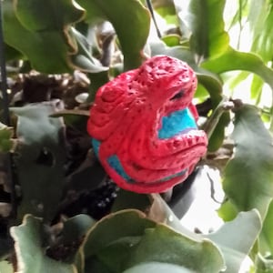 May include: A red and blue ceramic octopus figurine with detailed texture. The octopus is curled up with its tentacles wrapped around itself.