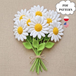 May include: A bouquet of crocheted daisies with white petals and yellow centers, green stems and leaves, tied with twine. The image includes the text "PDF PATTERN" in a white cloud-shaped bubble, along with the flags of Poland and the United States.