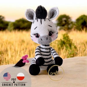 Puede incluir: Muñeca de cebra de ganchillo con rayas blancas y negras, pezuñas negras y una melena negra. La cebra tiene mejillas rosadas, largas pestañas y detalles grises. La muñeca está sentada sobre una superficie con un fondo borroso. La imagen incluye el texto "PDF CROCHET PATTERN".