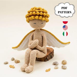 Puede incluir: Una muñeca de ganchillo con piel beige, ojos cerrados y cabello amarillo rizado, con grandes alas blancas con borde amarillo. La muñeca está sentada sobre un pequeño tronco de madera. Un gráfico en forma de nube contiene el texto PDF PATTERN, con los iconos de las banderas de Polonia, Estados Unidos e Italia debajo.