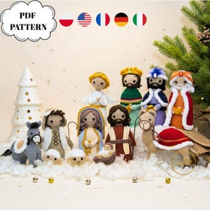 May include: A collection of crocheted nativity figures, including Mary, Joseph, baby Jesus, angels, and the three wise men. The figures are set on a fluffy white surface with a Christmas tree in the background. The image includes the text "PDF PATTERN".