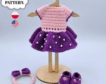 Puede incluir: Un conjunto de muñeca tejido a ganchillo que incluye un corpiño rosa claro y una falda morada con cuentas blancas, una diadema morada a juego con un lazo y un par de zapatos morados. Presentado en un colgador y soporte de madera. Texto PDF PATTERN.