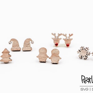 Puede incluir: Un conjunto de 10 pendientes de Navidad de madera. Los pendientes tienen forma de árboles de Navidad, gorros de Papá Noel, renos, pingüinos y copos de nieve. Los pendientes están hechos de madera natural y tienen un aspecto rústico.