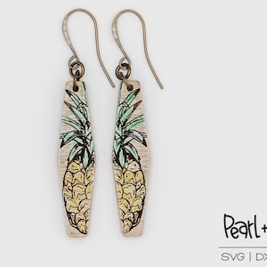 May include: A pair of wooden earrings with a pineapple design. The earrings are a light brown color with a yellow and green pineapple design. The earrings are attached to gold-colored hooks.