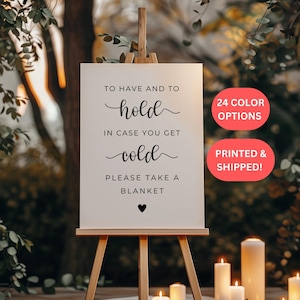May include: A white sign with black text on an easel reads "To have and to hold, in case you get cold, please take a blanket." The sign is surrounded by candles and greenery. The sign also has the text "24 color options" and "Printed & Shipped!" in red circles.