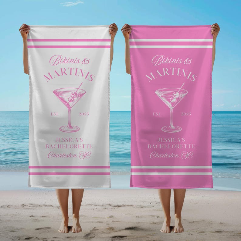 May include: Two white beach towels with pink stripes and text. The text reads "Bikinis & Martinis" with a martini glass graphic and "EST. 2025". The towels also say "Jessica's Bachelorette Charleston, SC". One towel is white and the other is pink.