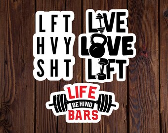 May include: Four white stickers with black text and images. The first sticker says "LFT HVY SHT". The second sticker says "LIVE LOVE LIFT". The third sticker says "LIFE BEHIND BARS" with a barbell image.