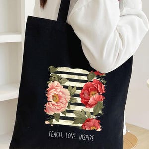 Puede incluir: Una taza de cer&aacute;mica blanca con asa negra y el texto "But First, Coffee" en negrita negra. La taza se encuentra sobre un fondo borroso, sugiriendo un ambiente acogedor.