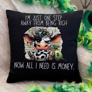 May include: Black throw pillow with a cartoon cow and the text "I'm just one step away from being rich. Now all I need is money."