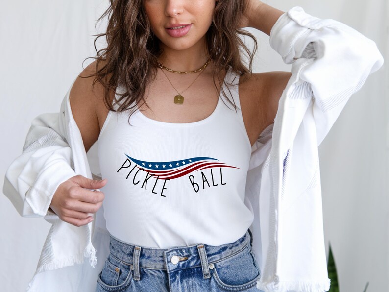 May include: White tank top with a red, white, and blue American flag design and the text "Pickle Ball".