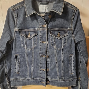 Puede incluir: Una chaqueta de mezclilla azul de lavado medio con cuello cl&aacute;sico, mangas largas con pu&ntilde;os abotonados y cierre frontal de botones. La chaqueta incluye dos bolsillos en el pecho con solapas abotonadas, dos bolsillos laterales y una etiqueta Amazon Essentials.