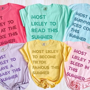 Puede incluir: Una colección de seis camisetas coloridas, cada una con una frase diferente impresa en negrita. Las camisetas son en tonos de rosa, verde menta, azul claro, lavanda, amarillo y rosa claro. Las frases comienzan con "MOST LIKLEY TO" seguido de una actividad de verano.