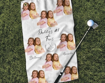 May include: White golf towel with the text "Daddy's #1 Fans" and a picture of golf clubs. There are nine pictures of children on the towel, each with their name written below their picture.