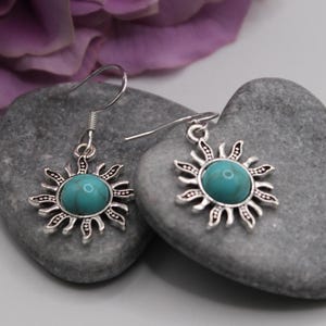 May include: A pair of silver earrings with turquoise stones set in a sunburst design.