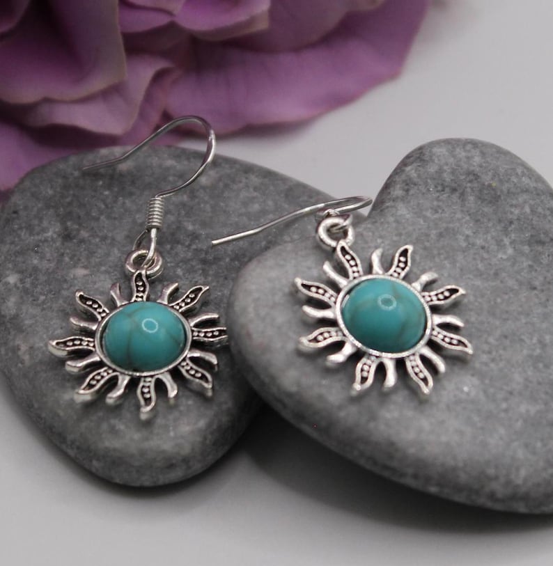 May include: A pair of silver earrings with turquoise stones set in a sunburst design.